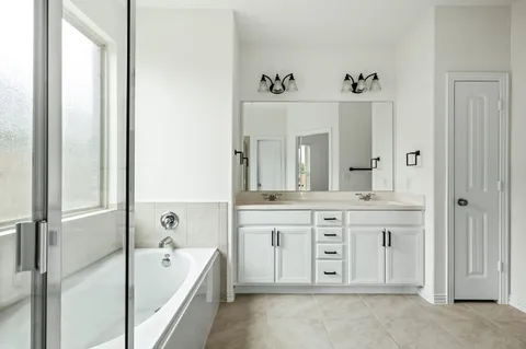 a spacious bathroom with a tub sink and mirror