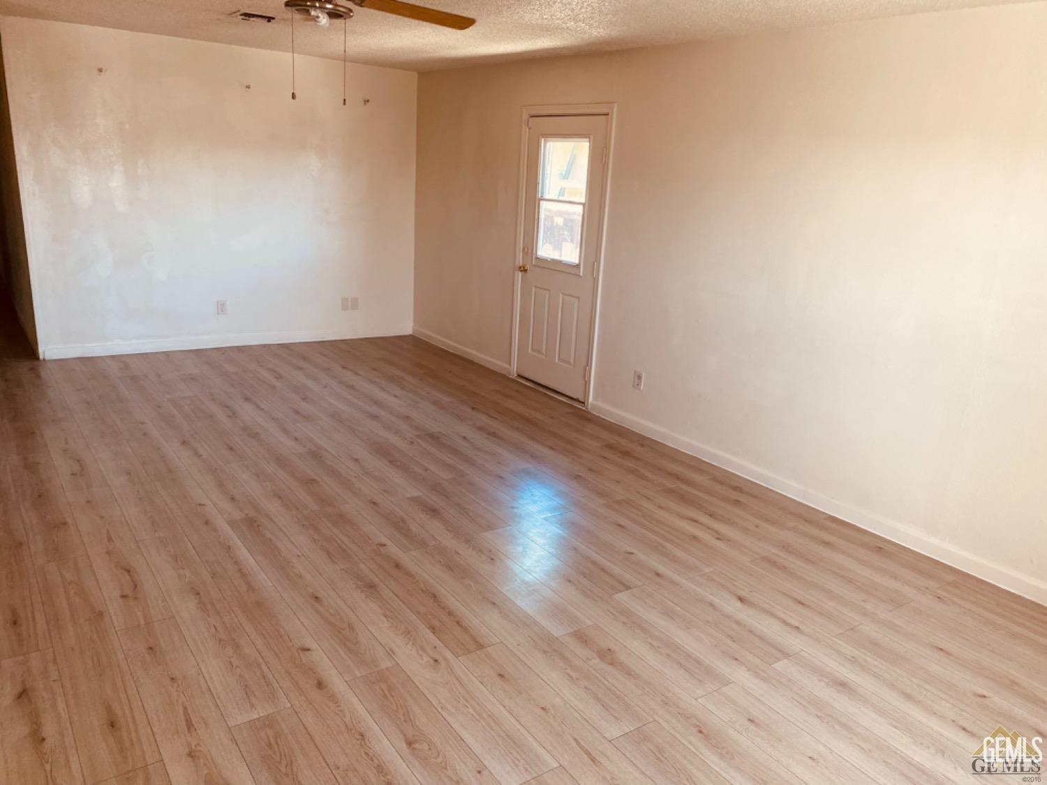 Undisclosed Address Delano, CA 93215 - Photo 3 of 7 an empty room with wooden floor and windows