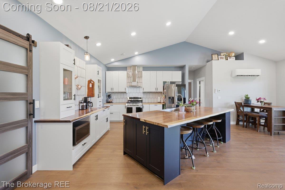 9161 East Coldwater Road Davison, MI 48423 - Photo 5 of 52 Kitchen featuring a large island with wood-finish countertop, white cabinetry with dark hardware, stainless steel appliances, and a patterned tile backsplash