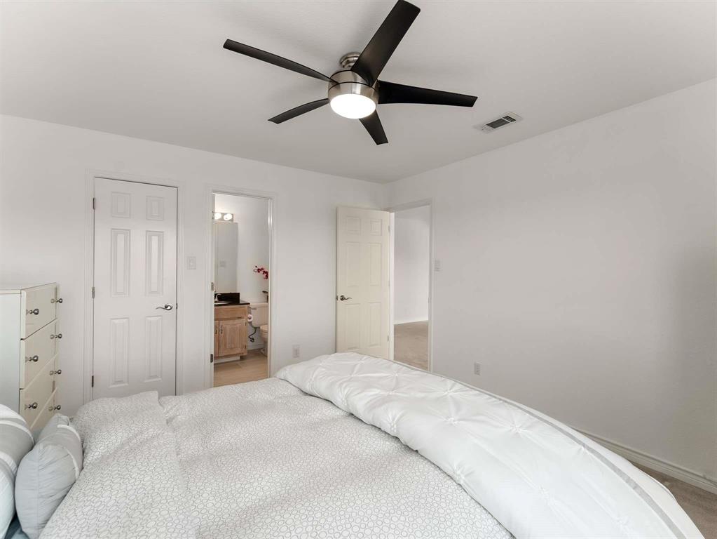 7436 Stoney Point Drive Plano, TX 75025 - Photo 14 of 40 a spacious bedroom with a bed and a ceiling fan