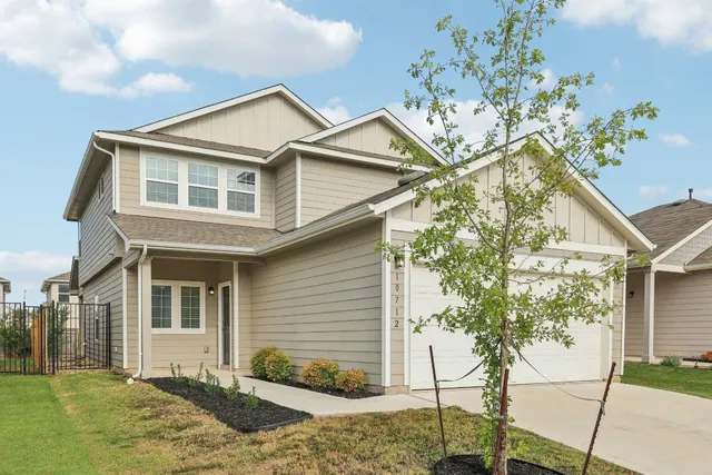 a front view of a house with a tree