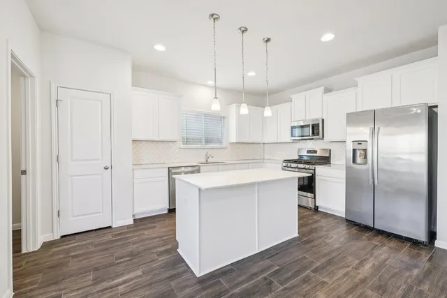 a kitchen with kitchen island white cabinets and stainless steel appliances