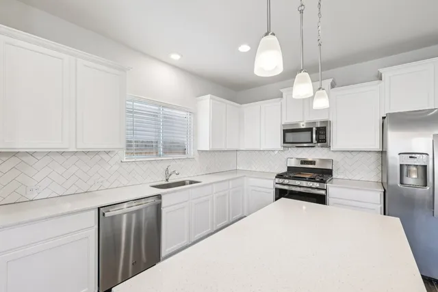 a kitchen with stainless steel appliances a sink a stove a refrigerator and cabinets