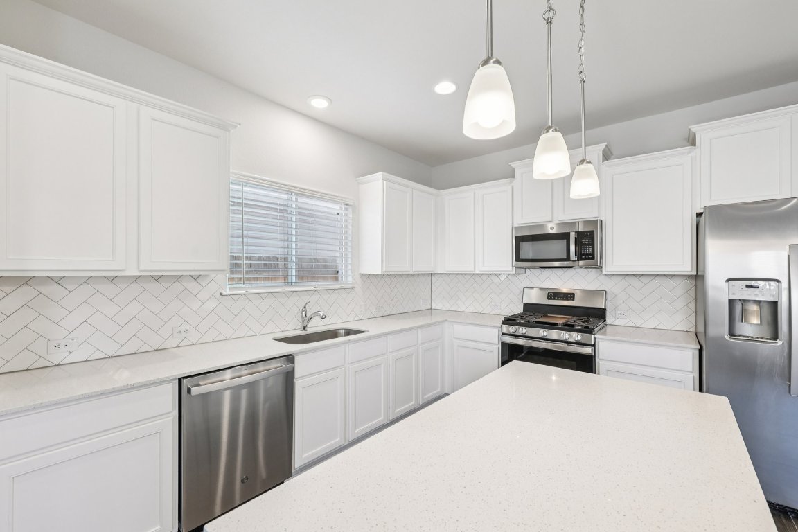 10712 Blacket Drive Austin, TX 78747 - Photo 13 of 40 a kitchen with stainless steel appliances a sink a stove a refrigerator and cabinets