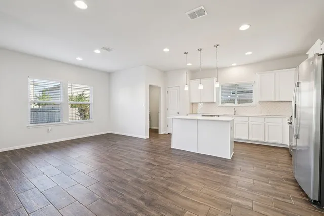 a large kitchen with kitchen island a sink wooden floor and white cabinets