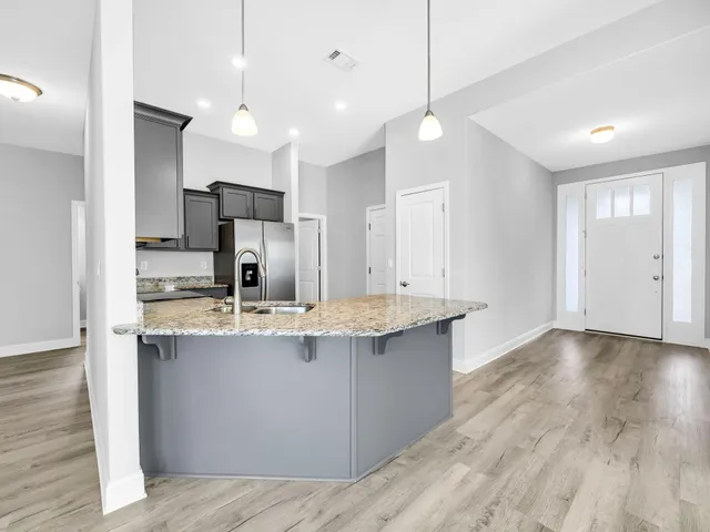 a view of a kitchen with kitchen island a sink stainless steel appliances and cabinets