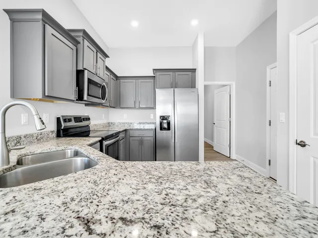 a kitchen with stainless steel appliances kitchen island granite countertop a refrigerator and a sink