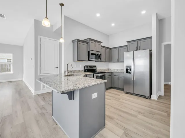 a kitchen with kitchen island granite countertop stainless steel appliances and wooden cabinets