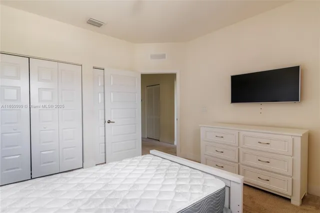 a bedroom with a bed and flat tv screen on the dresser