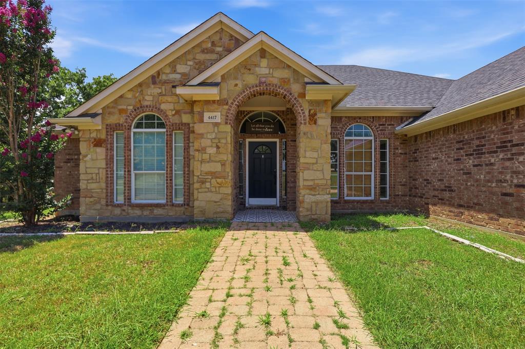 4417 Slayton Road Cleburne, TX 76031 - Photo 3 of 28 Exterior featuring a stone and brick facade with arched windows, a dark paneled entry door, and an asphalt shingle roof
