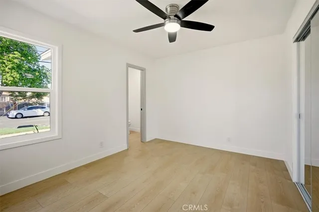 an empty room with windows and ceiling fan