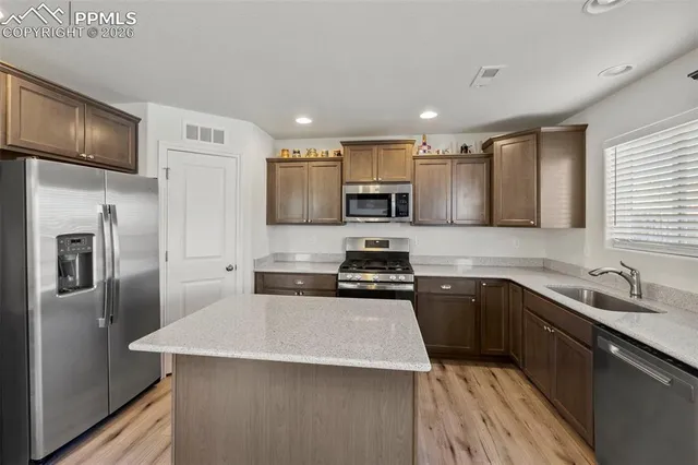 a kitchen with stainless steel appliances a sink stove refrigerator and cabinets
