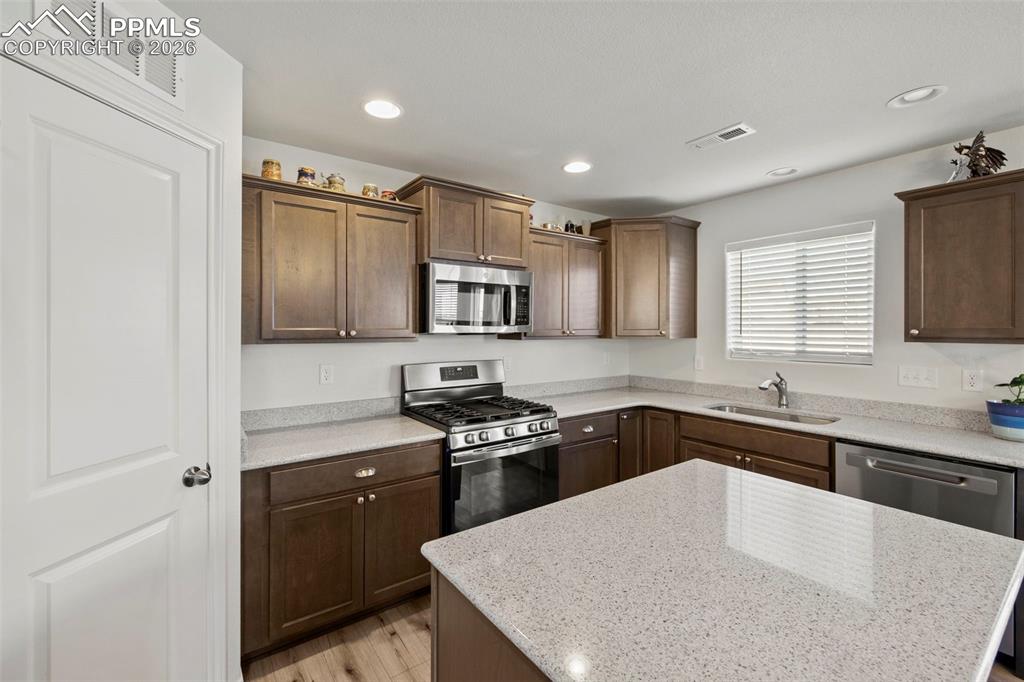 8151 Berwyn Loop Peyton, CO 80831 - Photo 7 of 39 a kitchen with a sink a stove a refrigerator a center island and cabinets