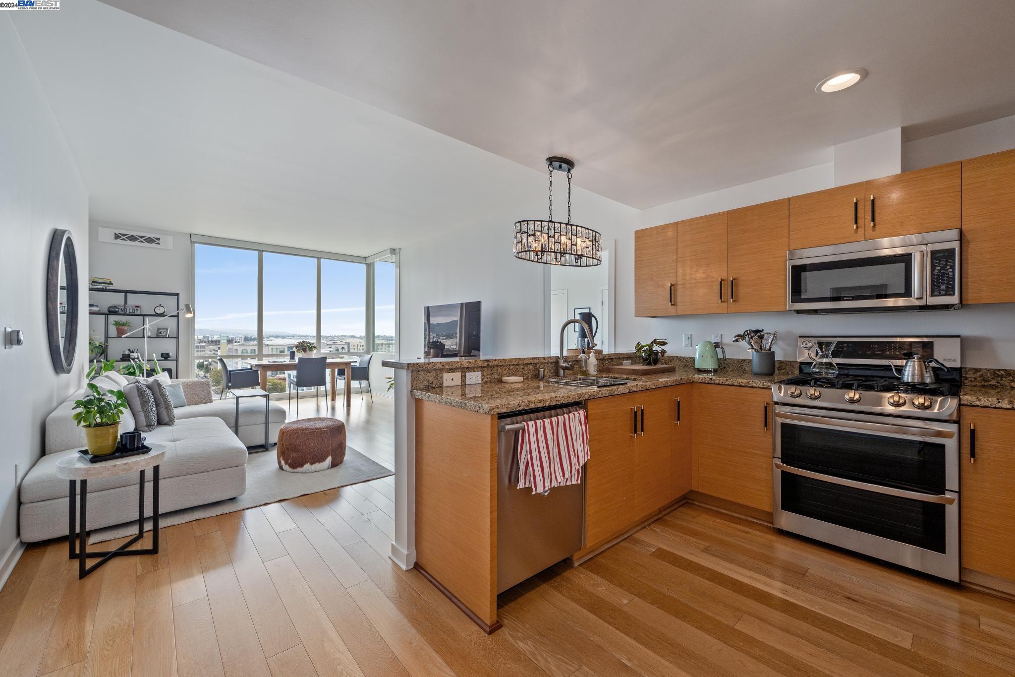 222 Broadway, Unit 1106 Oakland, CA 94607 - Photo 5 of 22 a kitchen with stainless steel appliances granite countertop a stove top oven a sink dishwasher a dining table and chairs with wooden floor