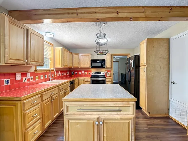 a kitchen with stainless steel appliances kitchen island granite countertop cabinets and wooden floor