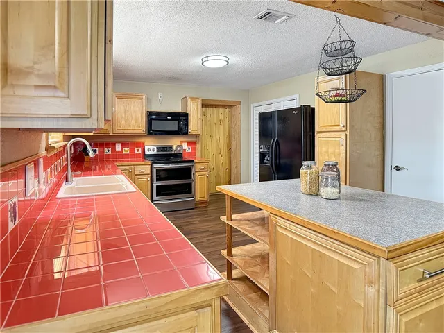 a kitchen with stainless steel appliances kitchen island granite countertop a stove a sink and a microwave
