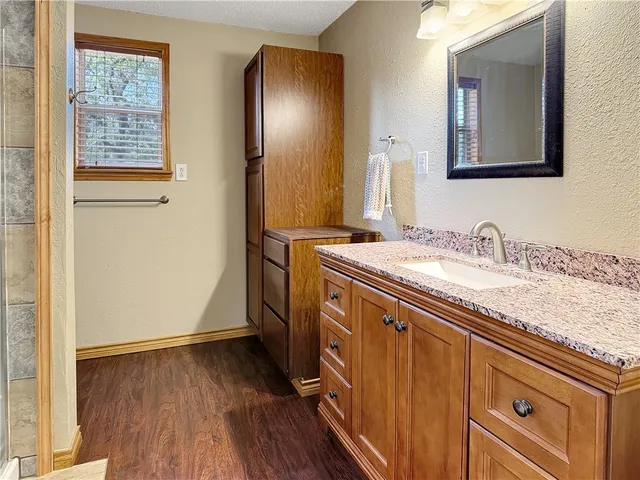 a bathroom with a granite countertop double vanity sink and mirror