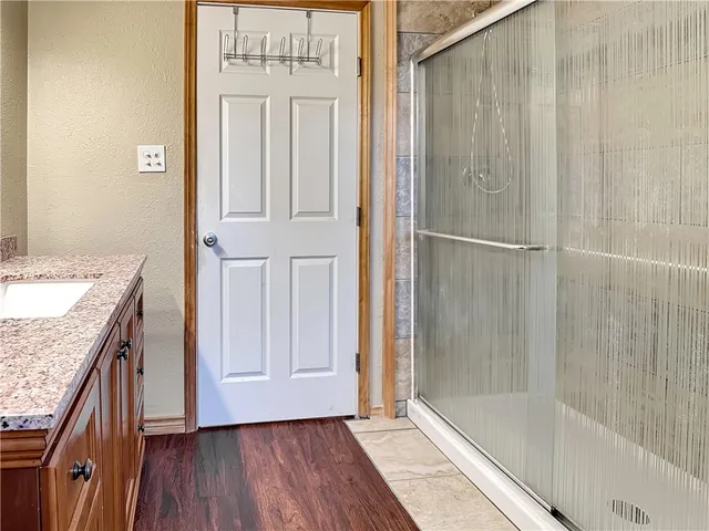 a bathroom with a granite countertop shower a sink and a wooden floor
