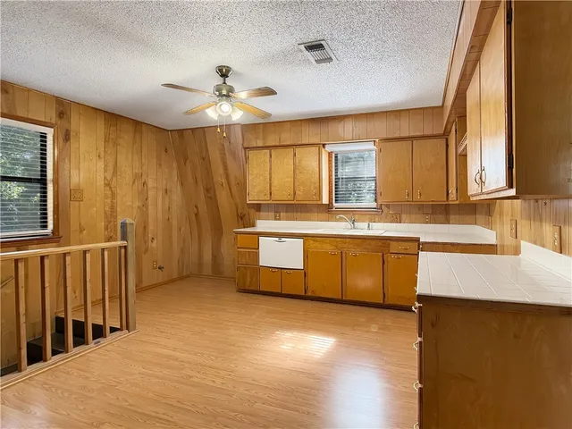 a kitchen with stainless steel appliances granite countertop a sink a stove top oven a chimney cabinets and wooden floor