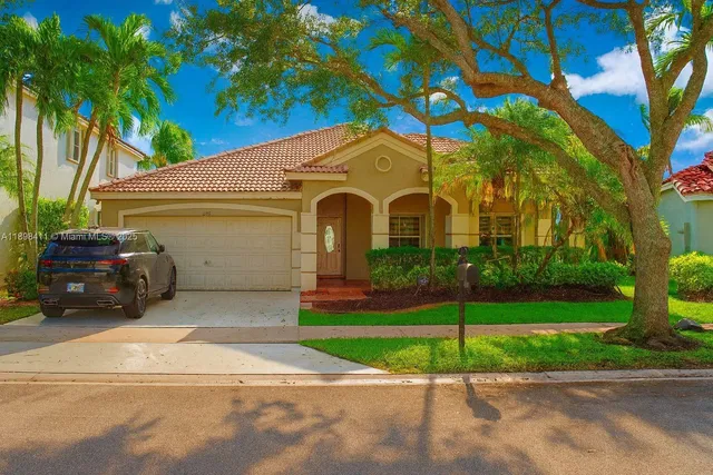 a front view of a house with a garden and trees