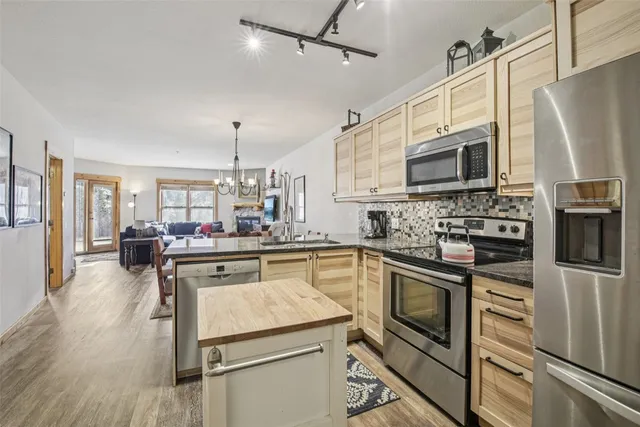 a kitchen with stainless steel appliances granite countertop a refrigerator a stove top oven a sink dishwasher and white cabinets with wooden floor