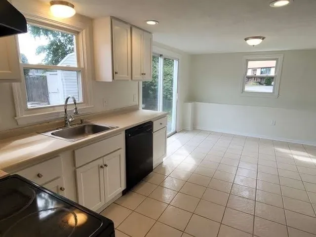 a kitchen with a sink a stove cabinets and a window