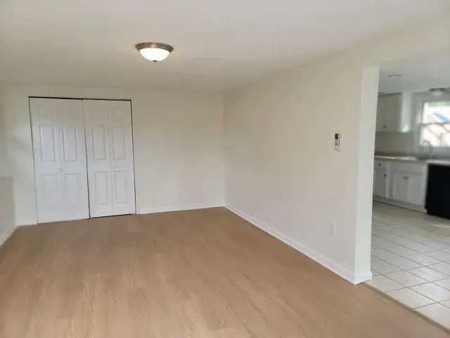 a view of an empty room with window and wooden floor
