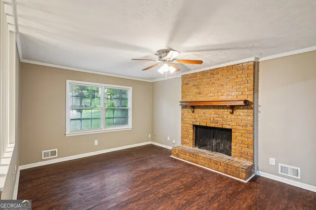 an empty room with fireplace wooden floor and windows