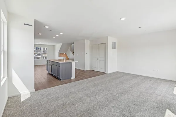 an empty room with wooden floor and kitchen view