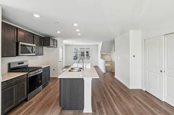a large kitchen with wooden floor and stainless steel appliances