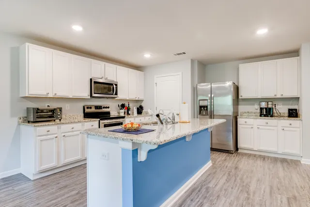 a kitchen with stainless steel appliances granite countertop grey cabinets a stove a sink and a microwave