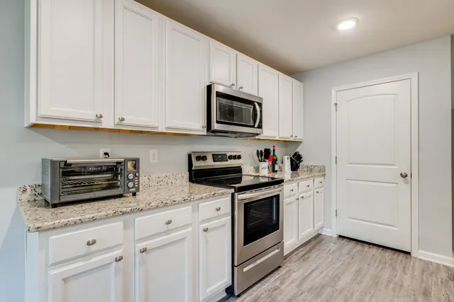 a kitchen with granite countertop white cabinets and stainless steel appliances