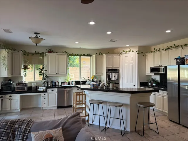 a kitchen with stainless steel appliances granite countertop a sink a stove a refrigerator cabinets and chairs