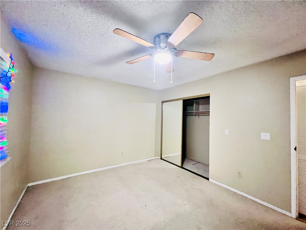 5048 Spencer Street, Unit C Las Vegas, NV 89119 - Photo 15 of 20 Unfurnished bedroom featuring a closet, a textured ceiling, carpet floors, and a ceiling fan