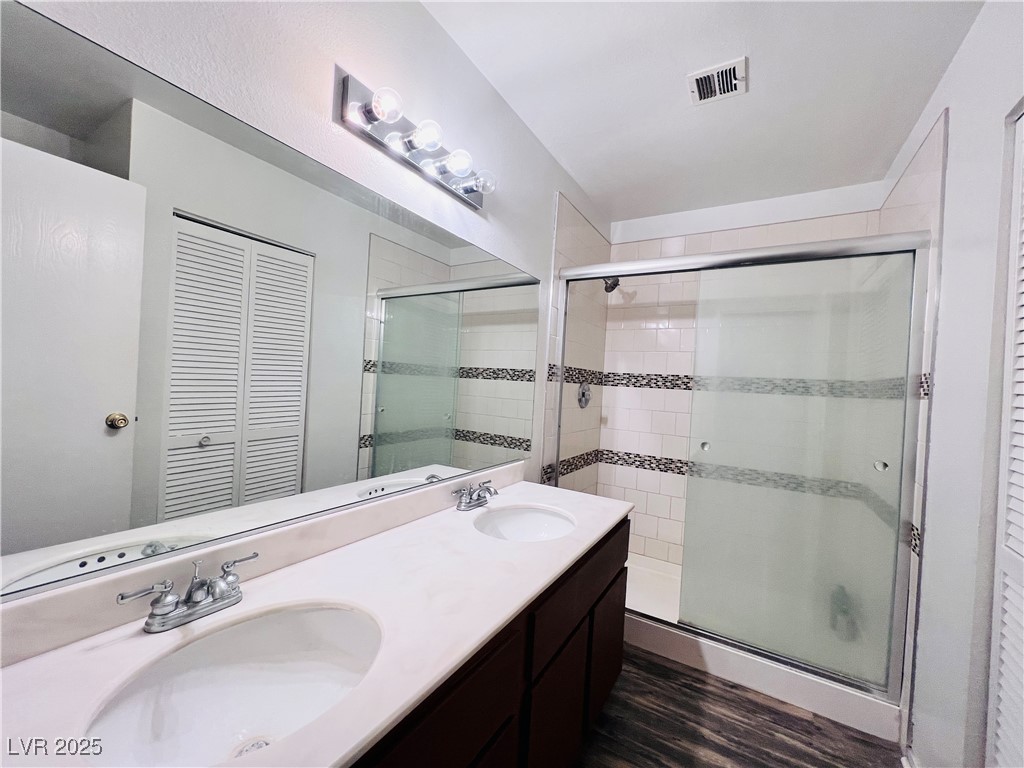5048 Spencer Street, Unit C Las Vegas, NV 89119 - Photo 16 of 20 Bathroom featuring a closet, double vanity, a shower stall, and dark wood-style flooring