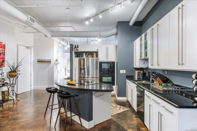 a kitchen with stainless steel appliances kitchen island granite countertop a table chairs in it and wooden floors