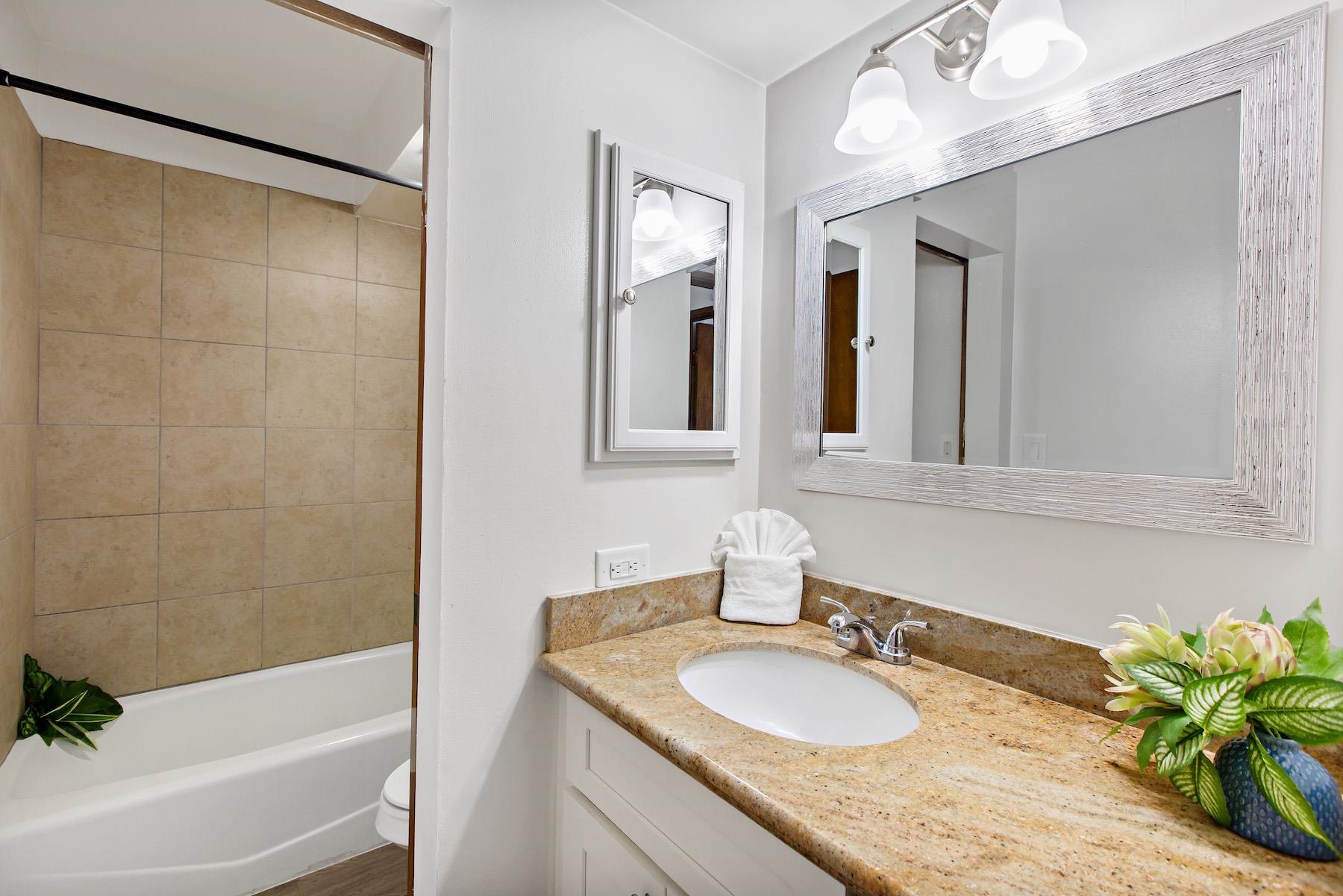 4310 Lower Honoapiilani Road, Unit 218 Lahaina, HI 96761 - Photo 15 of 30 a bathroom with a granite countertop sink a mirror a vanity and bathtub