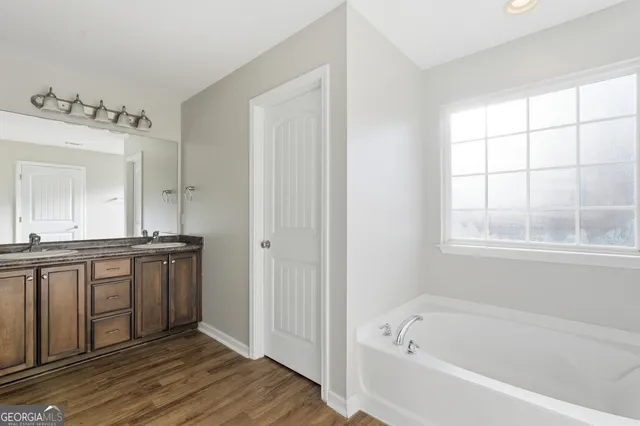 a bathroom with a granite countertop tub sink and mirror