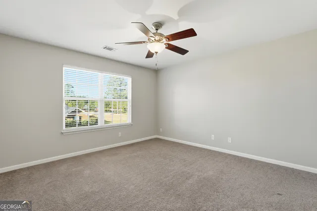 an empty room with window and ceiling fan