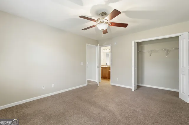 an empty room with closet and a ceiling fan