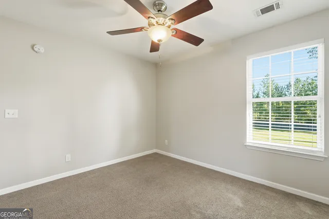 an empty room with a window and a fan