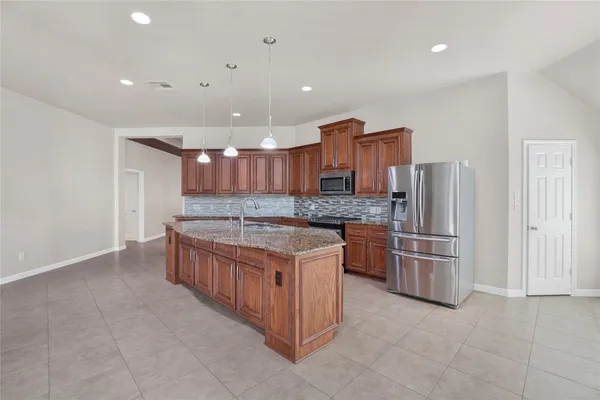 a large kitchen with stainless steel appliances granite countertop a stove and a refrigerator