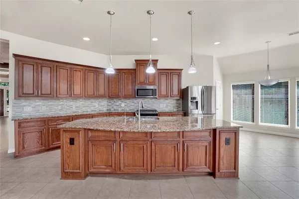 a kitchen with stainless steel appliances granite countertop a sink a stove and a wooden cabinets