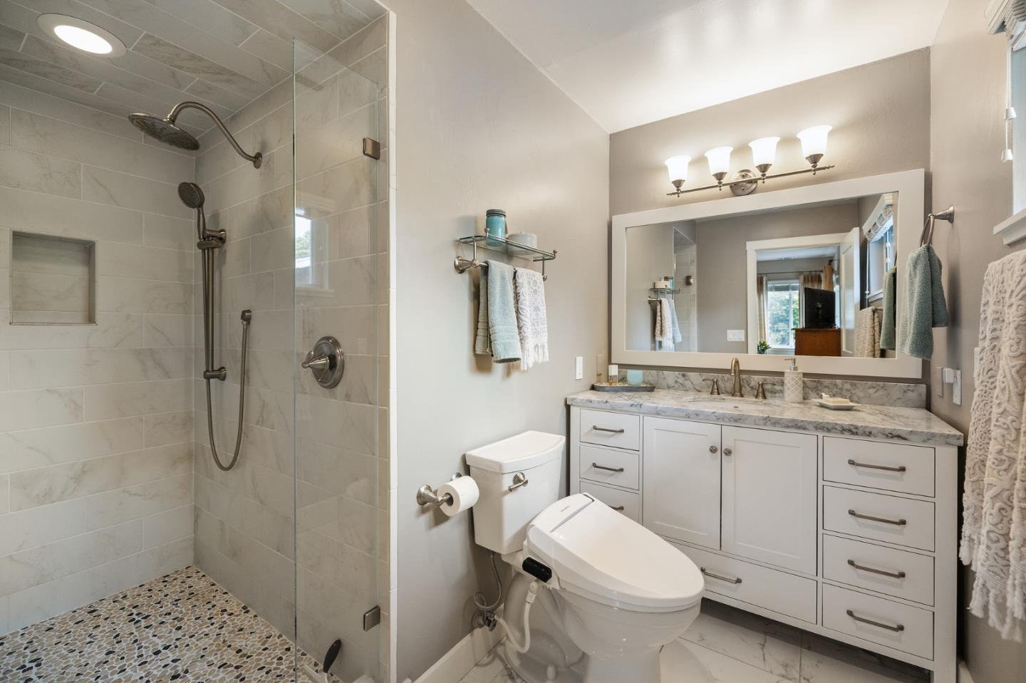 26571 Oliver Road Carmel, CA 93923 - Photo 27 of 63 a bathroom with a granite countertop sink toilet a large mirror a shower and a mirror