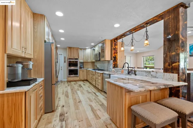a large kitchen with granite countertop a sink a counter top space and living room view