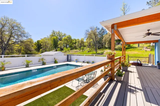 a view of swimming pool with seating space and trees in the background