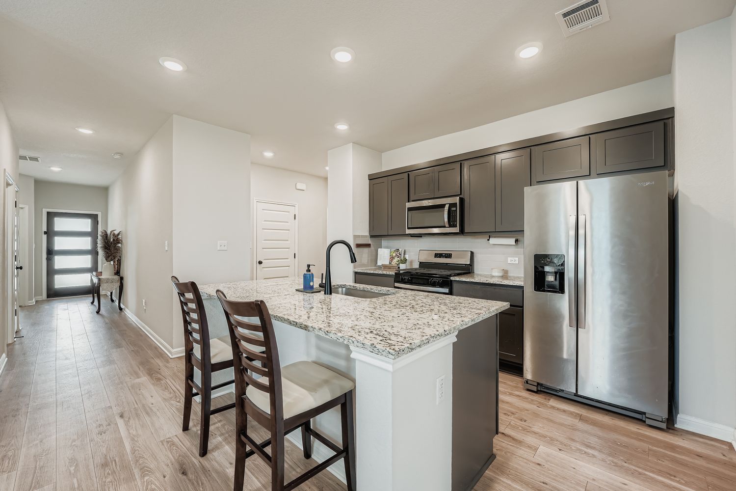 148 Gullivers Drive Elgin, TX 78621 - Photo 8 of 21 Kitchen with stainless steel appliances, a breakfast bar, light stone countertops, an island with sink, and light wood-type flooring