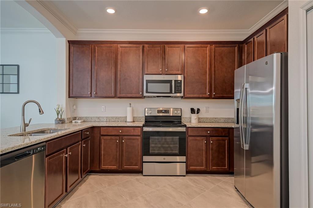 1774 Alameda Drive Naples, FL 34120 - Photo 9 of 29 a kitchen with stainless steel appliances granite countertop a stove top oven a sink and dishwasher a refrigerator with wooden cabinets