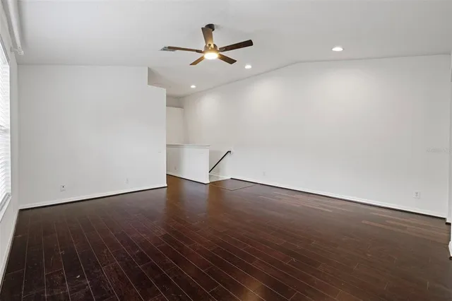 an empty room with wooden floor a ceiling fan and a window
