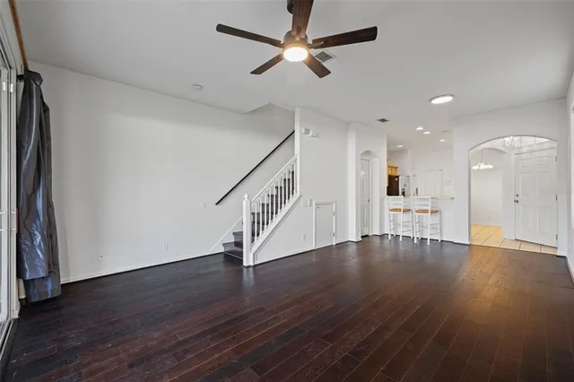 a view of an empty room with wooden floor and a ceiling fan